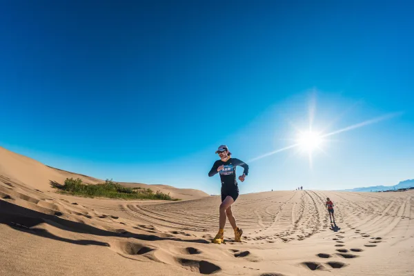 Coureur traversant les dunes du désert sous un soleil éclatant