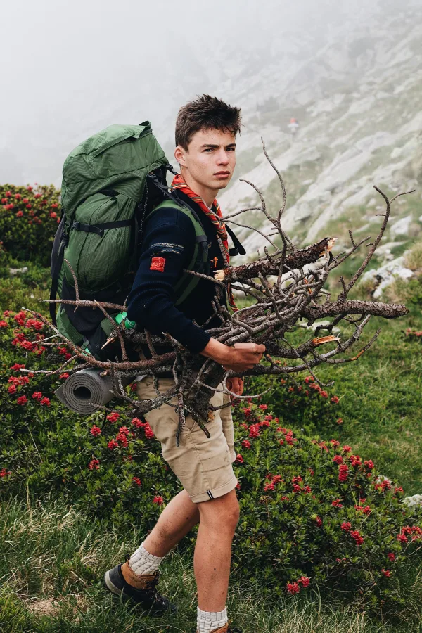 Jeune randonneur avec sac à dos transportant du bois en montagne